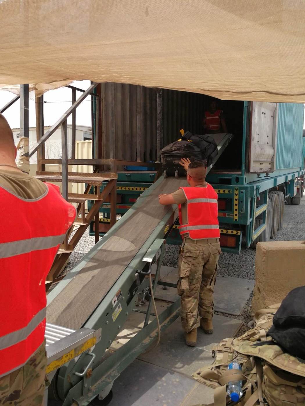 Team loading bags into a shipping container using a conveyor