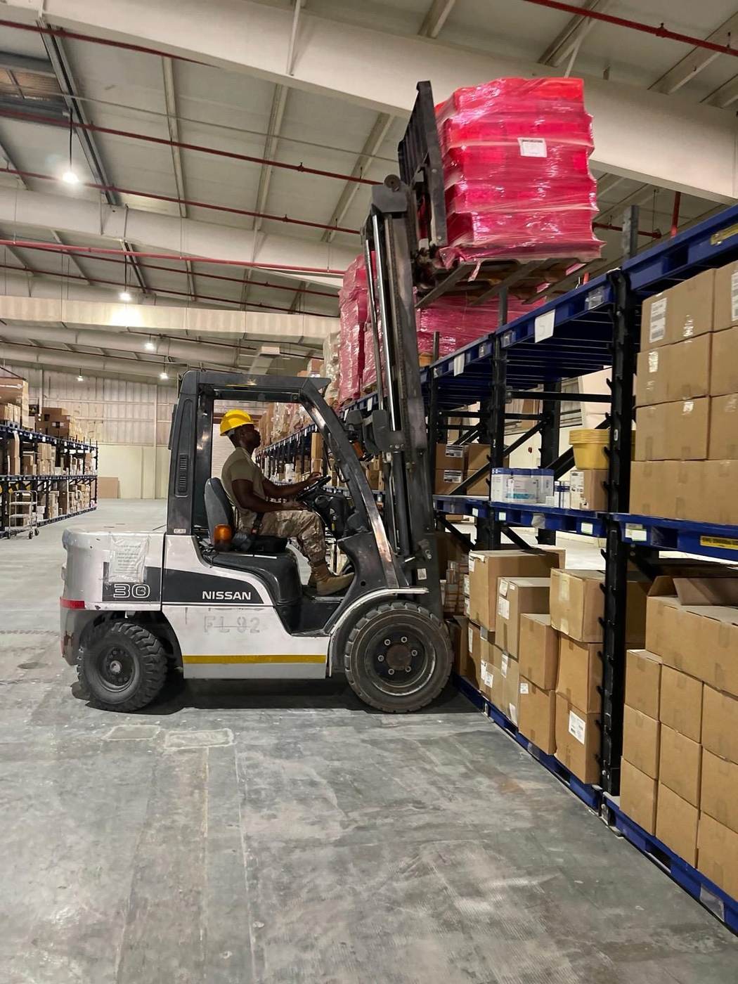 Forklift placing palletized goods into warehouse racks