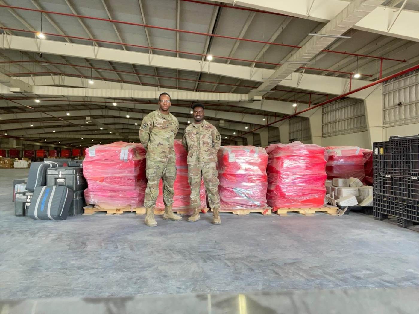 Logistics team standing with completed palletized load in a warehouse